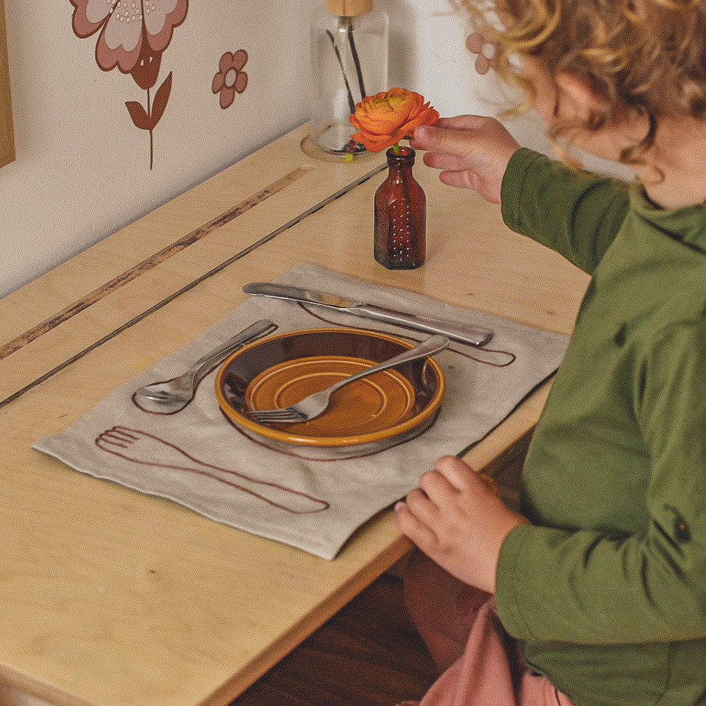 montessori placemat on table with child and vase