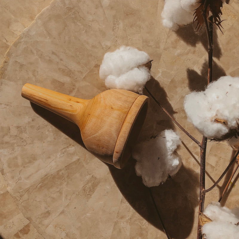 an image of a large wooden funnel laying on a light coloured natural table next to fluffy white cotton flowers