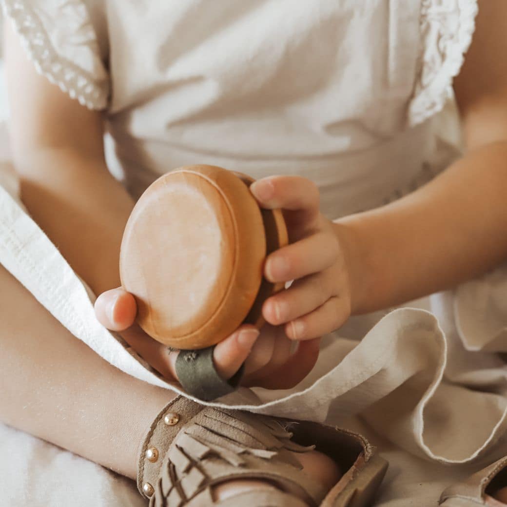 an image of a child wearing a white shirt holding a wooden yoyo