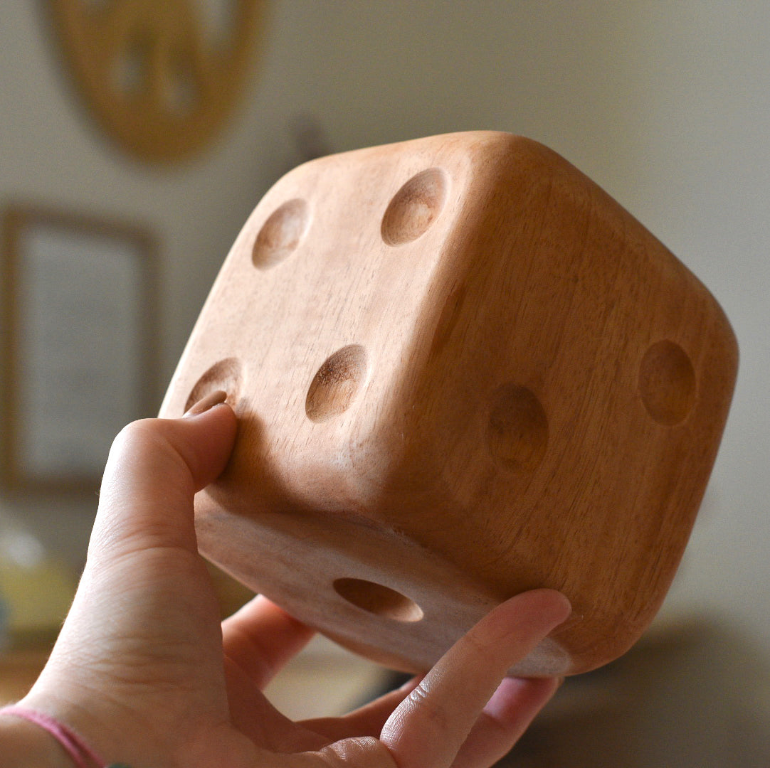 Image of a hand holding a large mahogany wooden dice