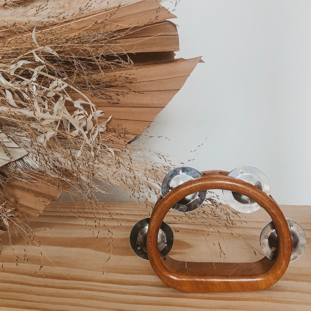 an image of a wooden instrument tambourine on a timber bench top next to natural dried flowers